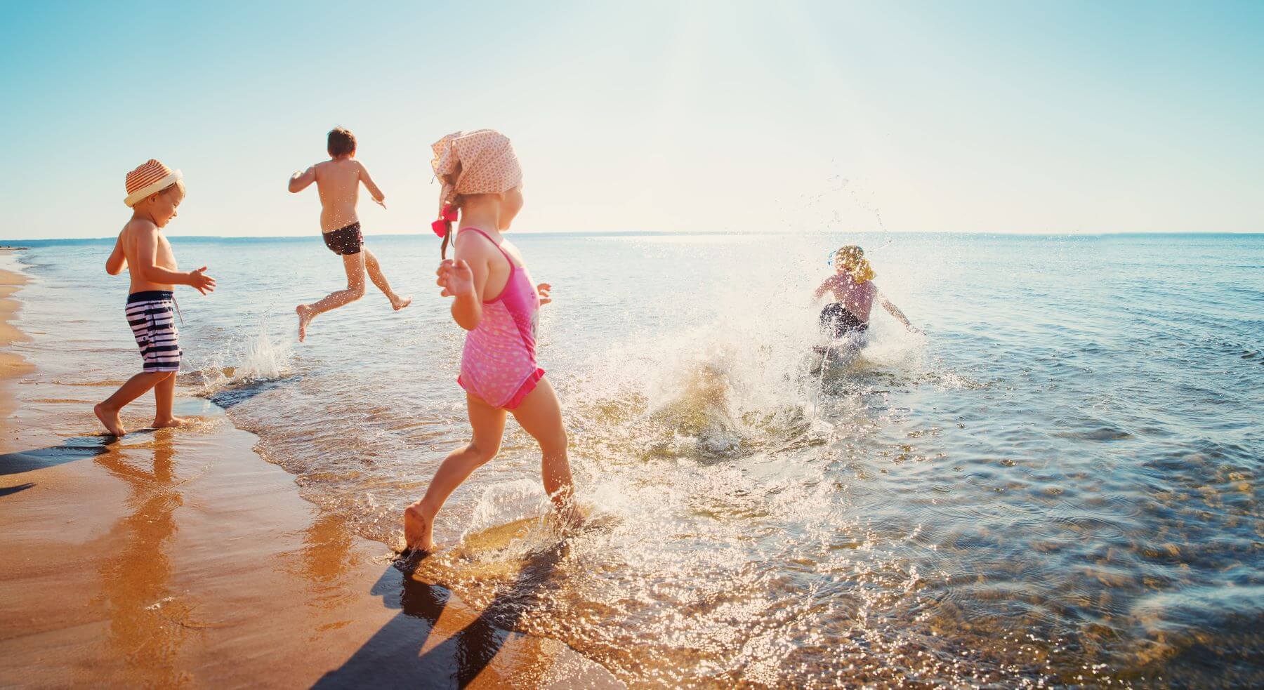 children running into the ocean on the beach fun kids laughter happy