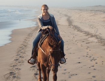 woman riding horseback on the beach
