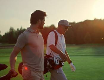 two men walking on golf course at twilight